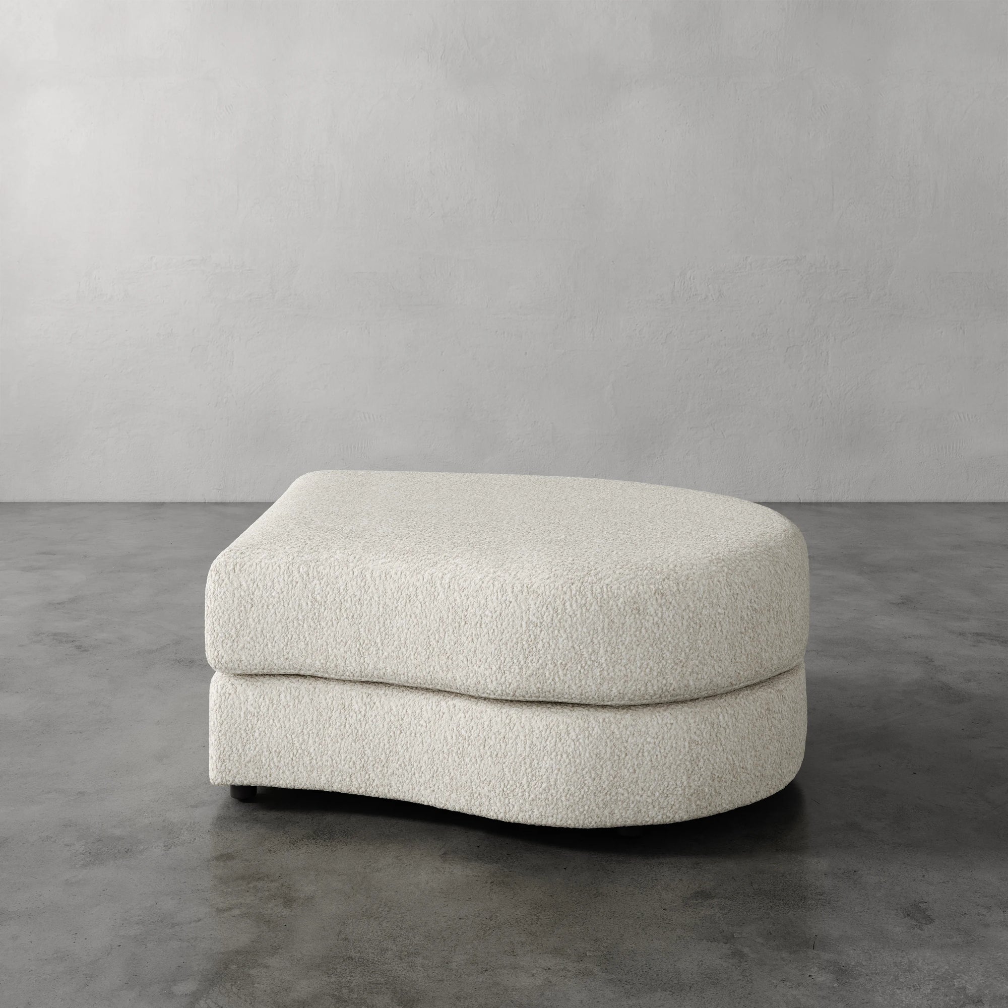 Lemieux Et Cie Rulmann Right Ottoman Beige ottoman on a gray floor with a neutral gray wall background