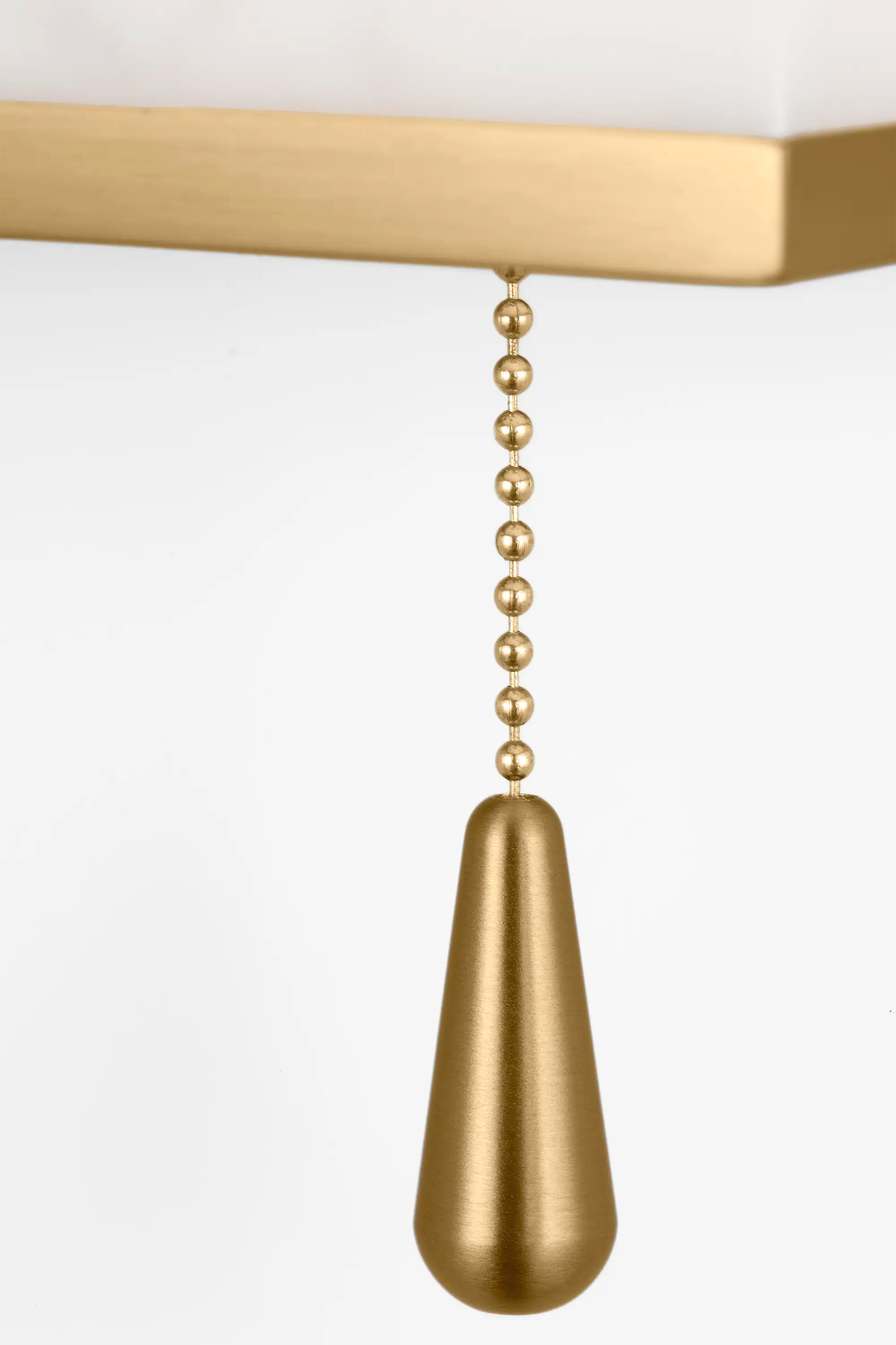 Lemieux et Cie Cleor Sconce detail, tapered pull chain in warm brass finish with beaded detail, shown against warm shade and white backdrop.