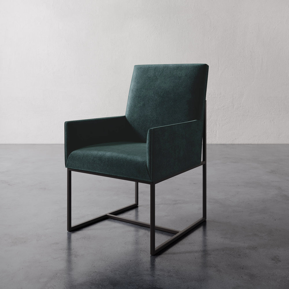Lemieux et Cie Dupont Dining Arm Chair in deep emerald green, geometric frame with straight lines, shown on polished concrete floor against white wall.
