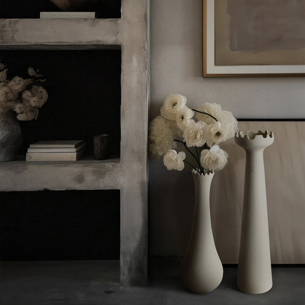 Lemieux et Cie Muguet Vase in matte white ceramic, sculptural vase with scalloped rim holding white ranunculus, styled beside concrete fireplace in neutral room.