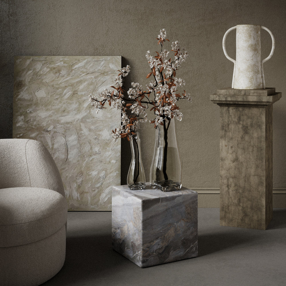 Lemieux et Cie Fleur de Verre in clear glass, sculptural vase with flowing contours, displayed on marble cube in a neutral sitting room.
