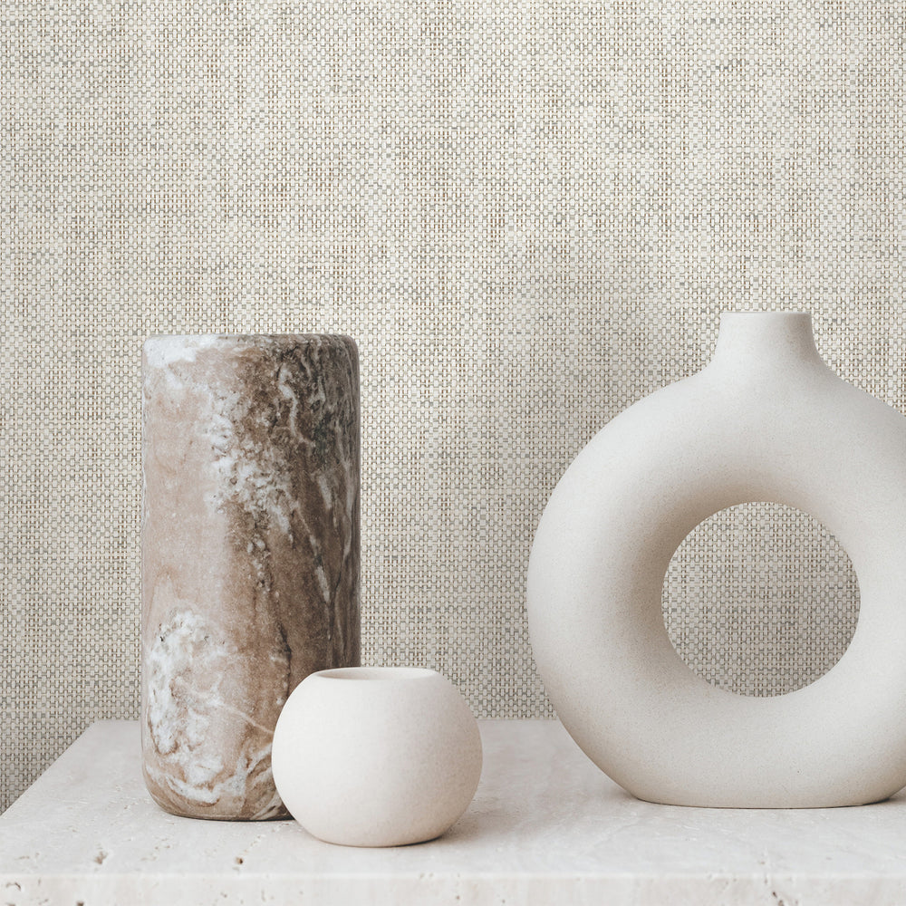 Lemieux et Cie Kami Paperweave wallcovering in charcoal gray, shown behind ceramic vases on stone surface with woven texture visible.