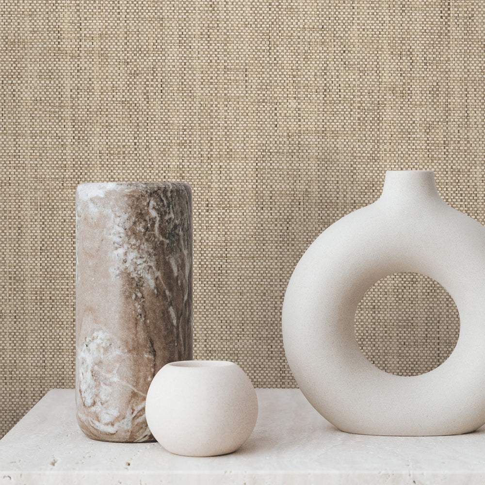 Lemieux et Cie Zora Waves in black on tan brown, woven wallcovering with wave-pattern texture, shown behind sculptural ceramic vases on stone surface.