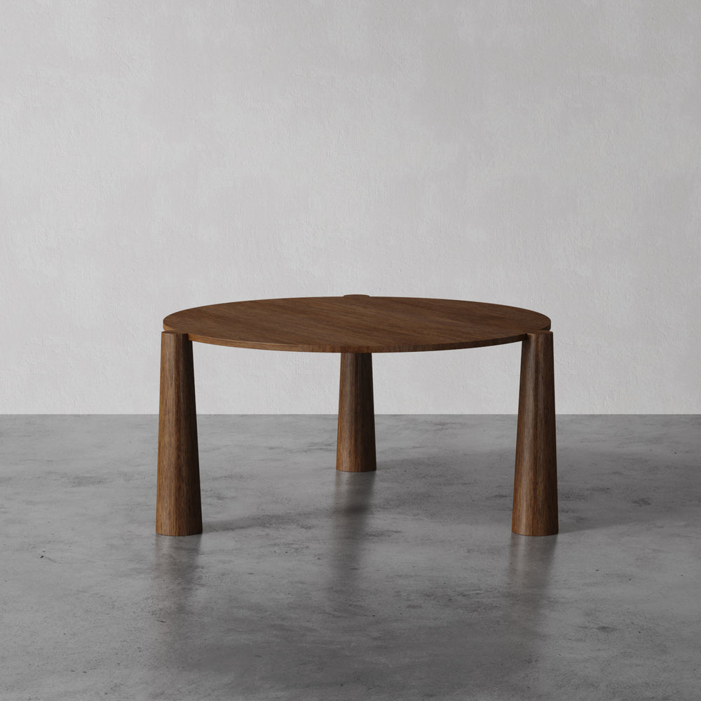 Lemieux et Cie Girard Dining Table in oak with flared cylindrical legs, shown on concrete floor against neutral plaster walls.