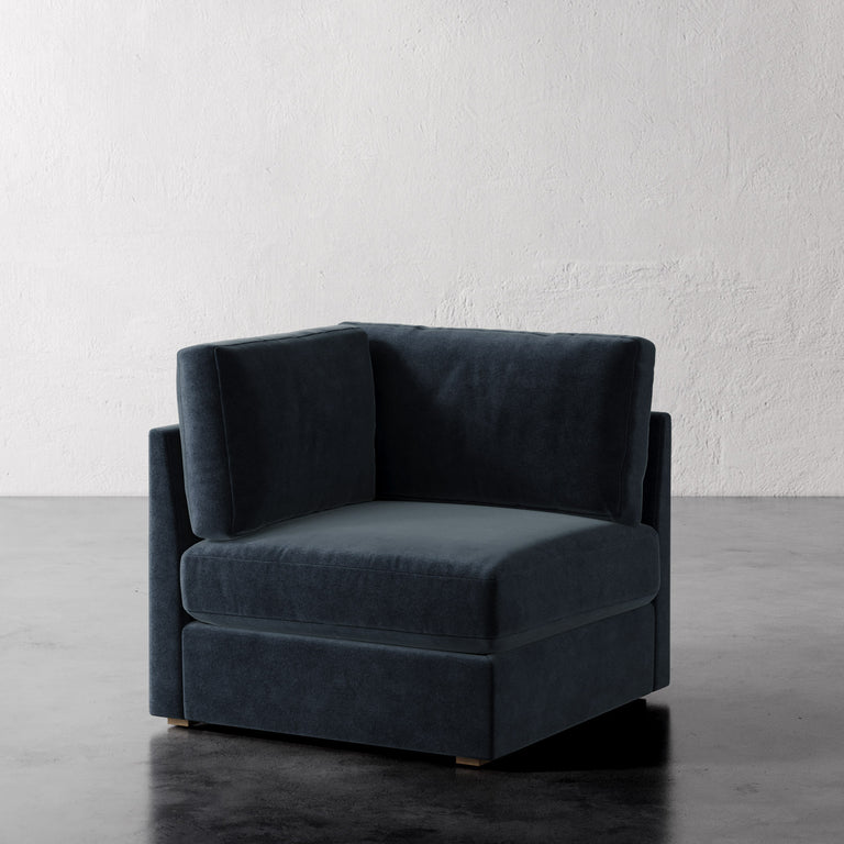 Lemieux Et Cie Chanaux Corner Chair Blue armchair on a gray floor with a white wall background