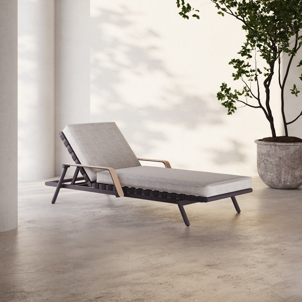 Lemieux et Cie Hudson Chaise Lounge with adjustable back and warm-toned arms, chaise lounge on stone floor in bright daylight with potted tree beside white walls.