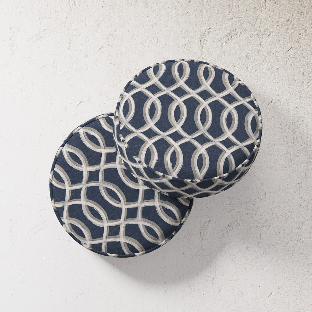 Lemieux et Cie Outdoor Pillow in Gatework Navy, round cushions with geometric ivory trellis pattern, shown against textured plaster wall.