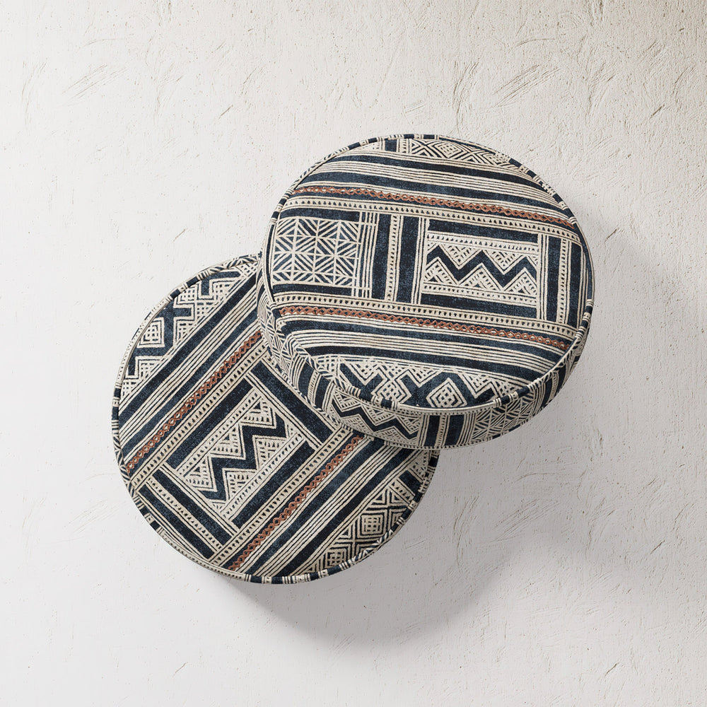 Lemieux et Cie Outdoor Pillow in Indigo Inlet, round cushions with geometric indigo and ivory pattern, shown against textured plaster wall.