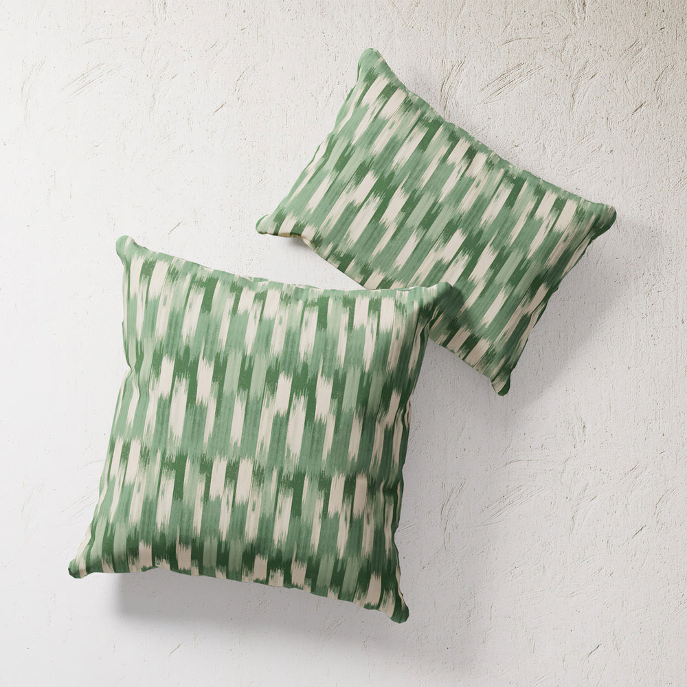 Lemieux et Cie Outdoor Pillow in Green French Flamme ikat pattern, pair of square pillows shown against textured plaster wall.