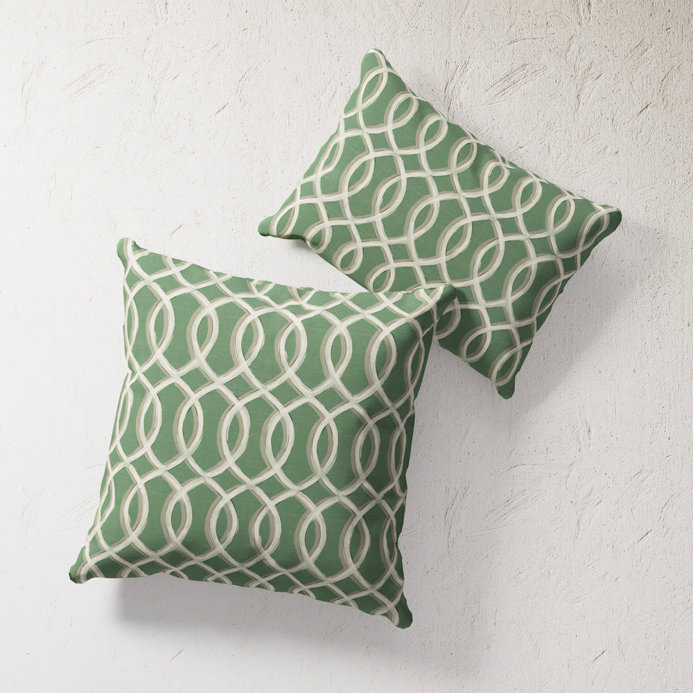 Lemieux et Cie Outdoor Pillow in green and cream geometric trellis pattern, two throw pillows shown against textured white plaster wall.
