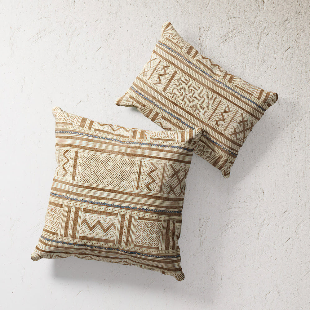 Lemieux et Cie Raw Umber Inlet Outdoor Pillow in warm geometric stripe pattern, two square pillows shown on textured plaster wall.