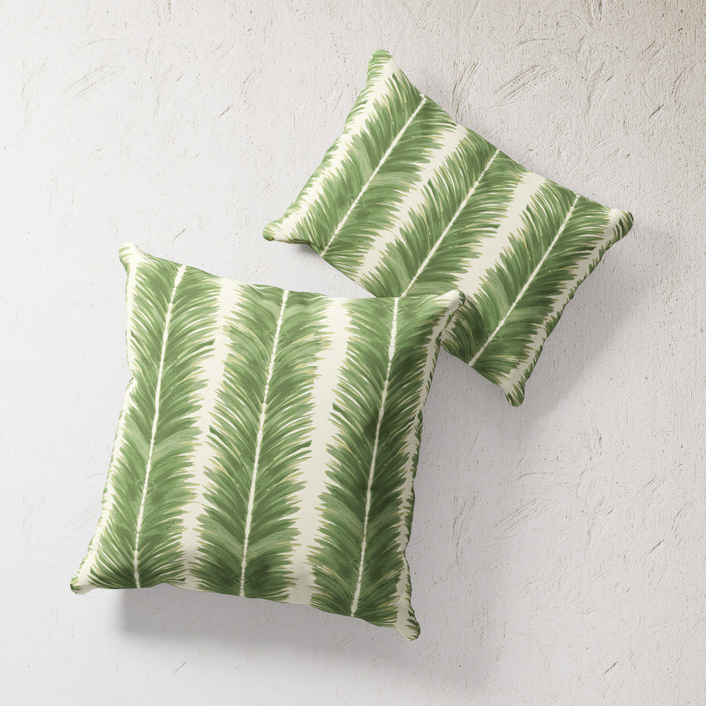 Lemieux et Cie Outdoor Pillow in Palm Stripe, green and ivory chevron pattern pillows, shown on textured plaster backdrop.