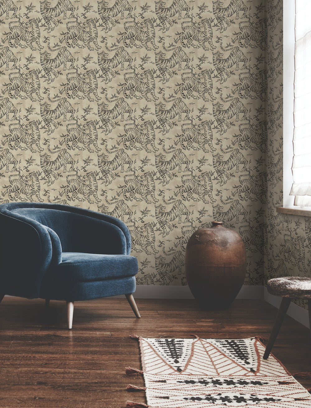 Lemieux et Cie Orly Tigers wallpaper in charcoal gray on powder white, shown in sitting room with blue velvet chair and handwoven rug on wood floors.