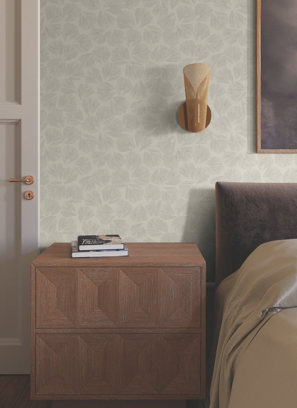 Lemieux et Cie Elora Leaf wallpaper in taupe brown with metallic veining, shown in bedroom with geometric nightstand and warm bedding.