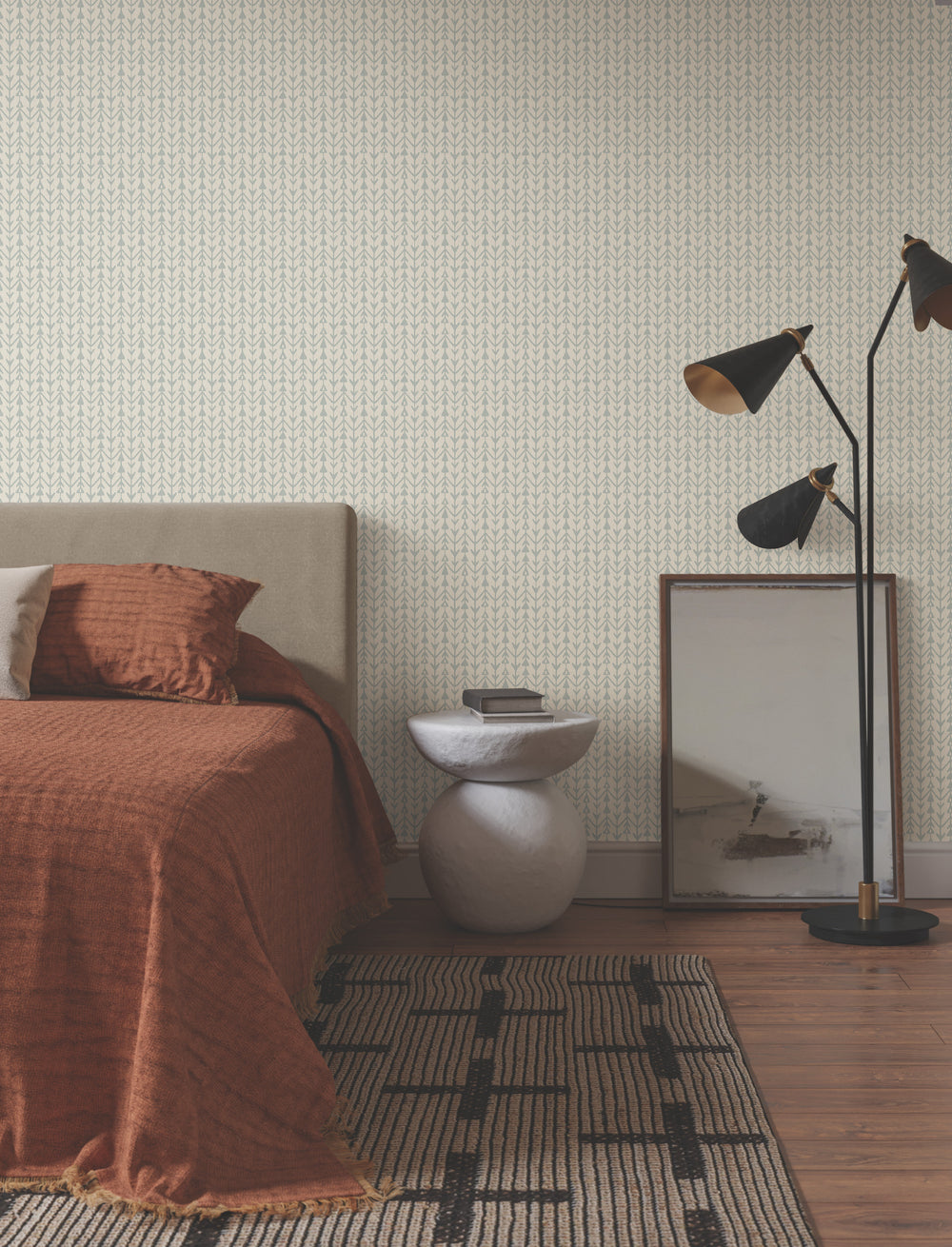 Lemieux et Cie Martigue Stripe in sage green, striped rug shown bedside on wood flooring, styled with patterned wallpaper and warm rust linens.