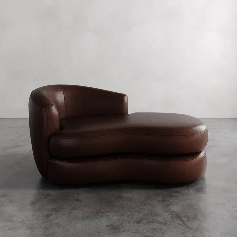 Lemieux et Cie Rulmann Leather Left Arm Chaise in rich brown leather, low-slung sculptural chaise with rounded back, shown on concrete floor against neutral wall.