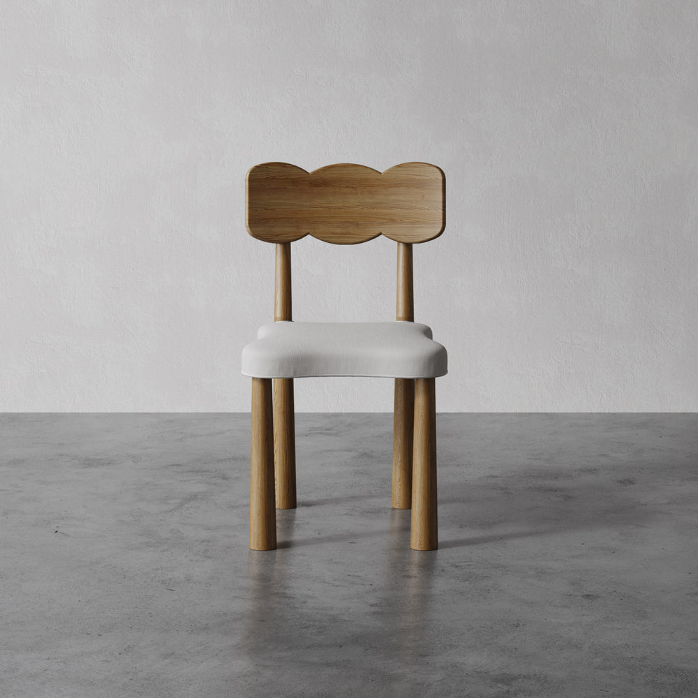 Lemieux et Cie solid oak dining chair in walnut finish with sculpted bow-shaped back and upholstered seat, on concrete floors against neutral walls.