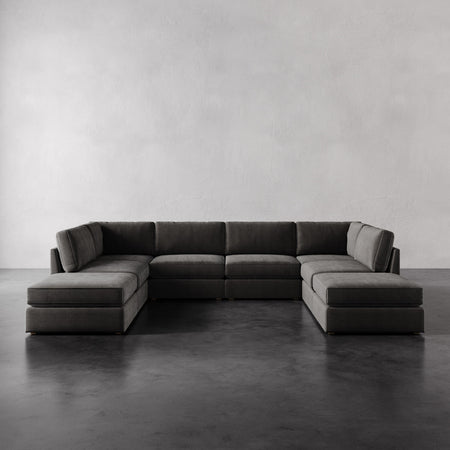 Lemieux et Cie Chanaux 8-Pc Sectional in charcoal, low-profile modular sofa with dual chaises, shown on dark concrete floor against white walls.