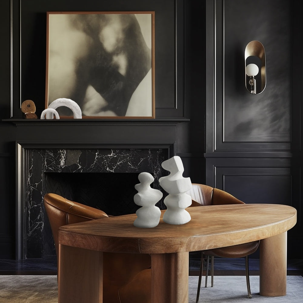 Lemieux et Cie Mouren Sculpture in white concrete, organic stacked forms displayed on round wood dining table in dark-paneled room with marble fireplace.
