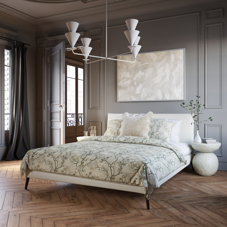 Lemieux et Cie Cornet 4 Light Extra Large Chandelier, a luxury lighting fixture, hangs above a bed with layered bedding in a calm bedroom.