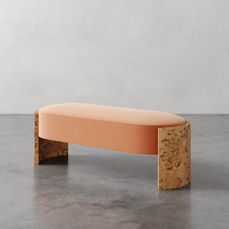 Lemieux et Cie Benoit Custom Upholstered Bench in blush velvet with curved Maple burl legs, shown on polished concrete floor against textured plaster wall.