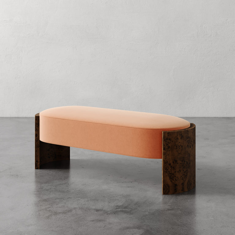 Lemieux et Cie Benoit Custom Upholstered Bench in blush with curved Maple burl legs, shown on polished concrete in soft plaster-walled room.