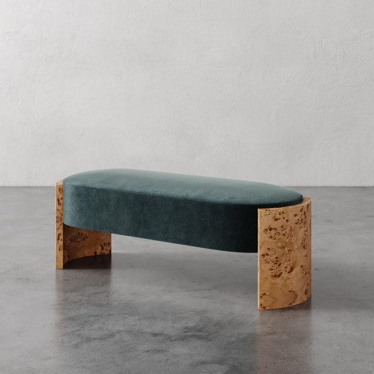 Lemieux et Cie Benoit Custom Upholstered Bench with curved Maple burl legs and deep teal velvet seat, shown on concrete floor against plaster wall.