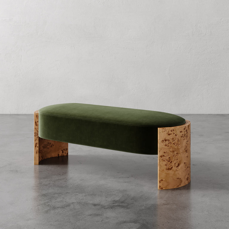 Lemieux et Cie Benoit Bench in olive velvet with curved Maple burl legs, upholstered bench on polished concrete floor against textured plaster walls.