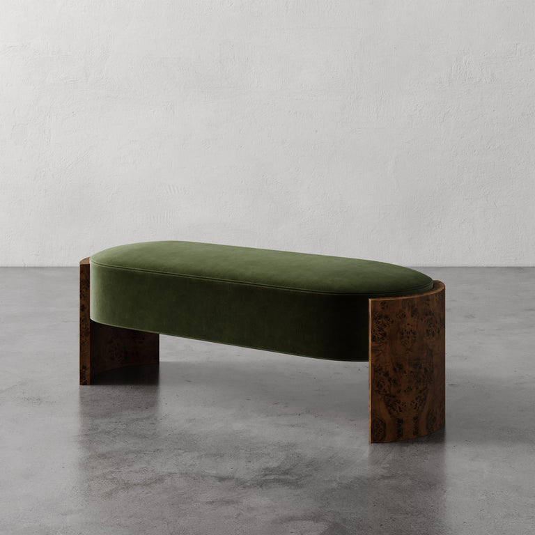 Lemieux et Cie Benoit Custom Upholstered Bench in green velvet with curved Maple burl legs, shown on polished concrete floor against plaster walls.