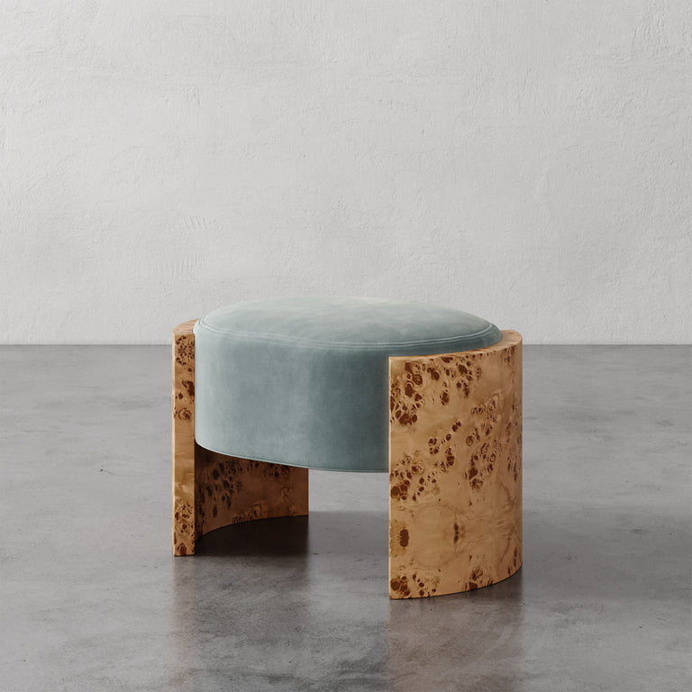 Lemieux et Cie Benoit Ottoman in seafoam velvet with burl wood base, low-profile seating on stone floor against textured plaster walls.