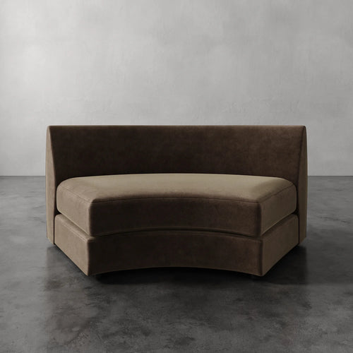 Lemieux Et Cie Rulmann Wedge Brown curved sofa against a gray wall