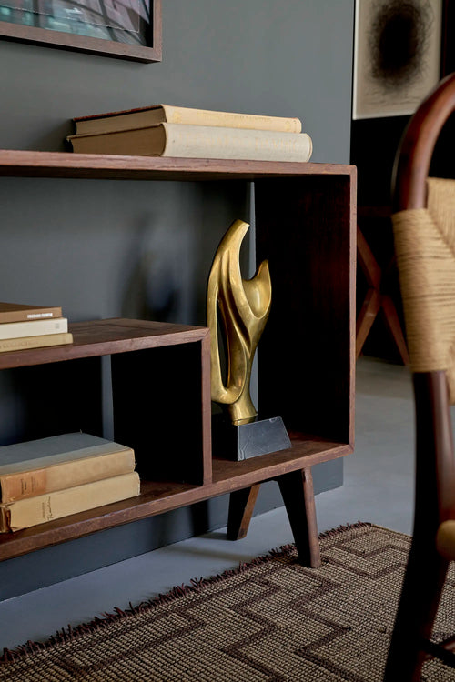 Lemieux et Cie Pierre Jeanneret bookcase in solid teak - styled three-quarter view showing the open shelves, a brass sculpture and the tapered splayed legs