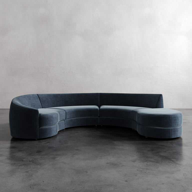 Lemieux Et Cie Rulmann 4-Piece Left Sectional Blue curved sofa on a gray floor with a plain wall background