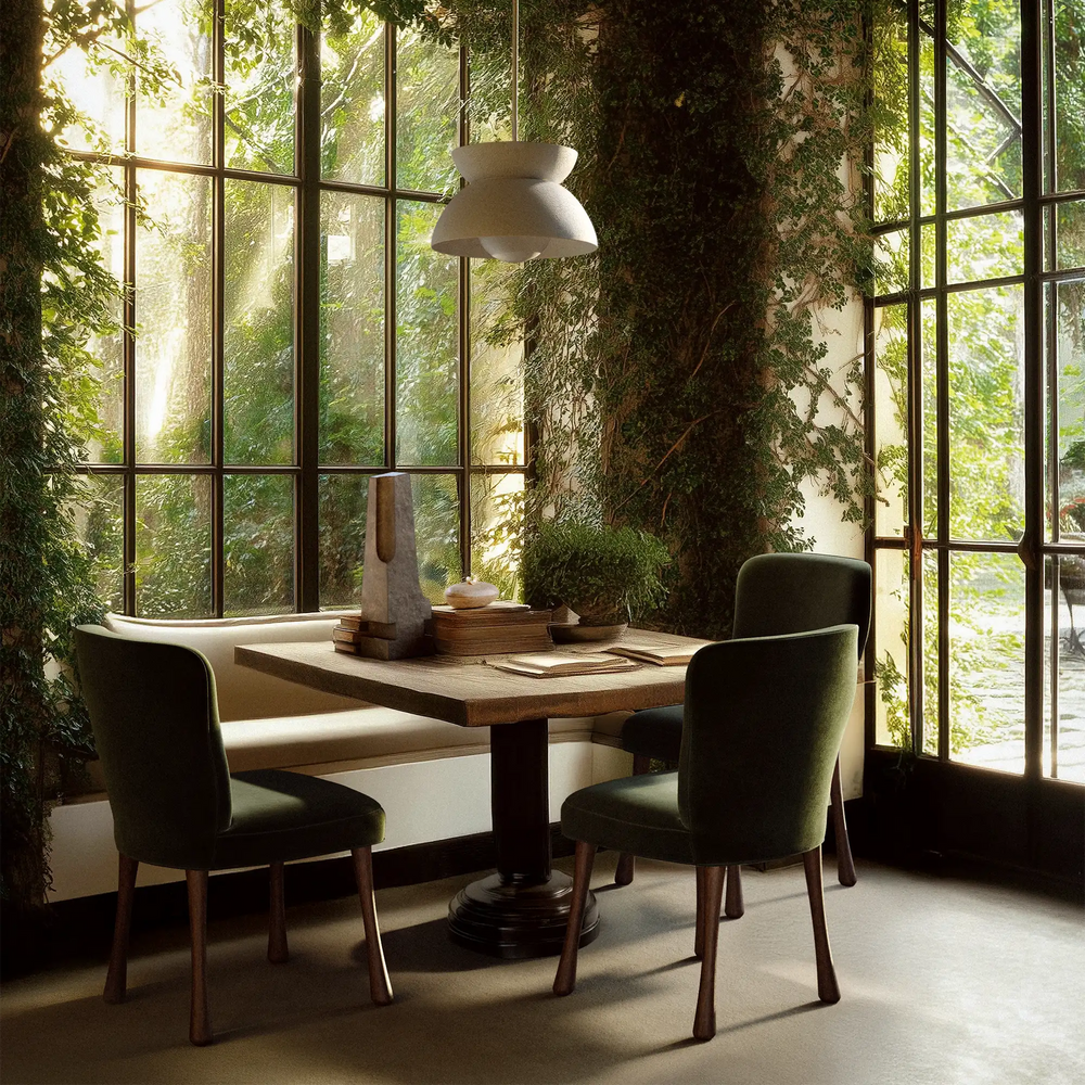 Lemieux et Cie Brunoy Chair in olive green velvet, channeled lounge chair in sunlit dining room with steel-framed windows and climbing greenery.