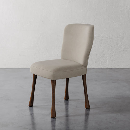 Rozette Dining / Side Chair (Leather) Beige with wooden legs on a gray floor and white wall background