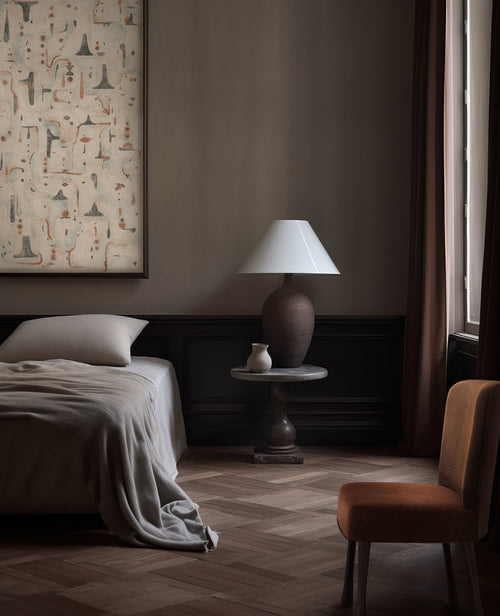 Lemieux et Cie La Fougère abstract print in warm tones, framed artwork above bed in a bedroom with herringbone wood floors and dark wainscoting.