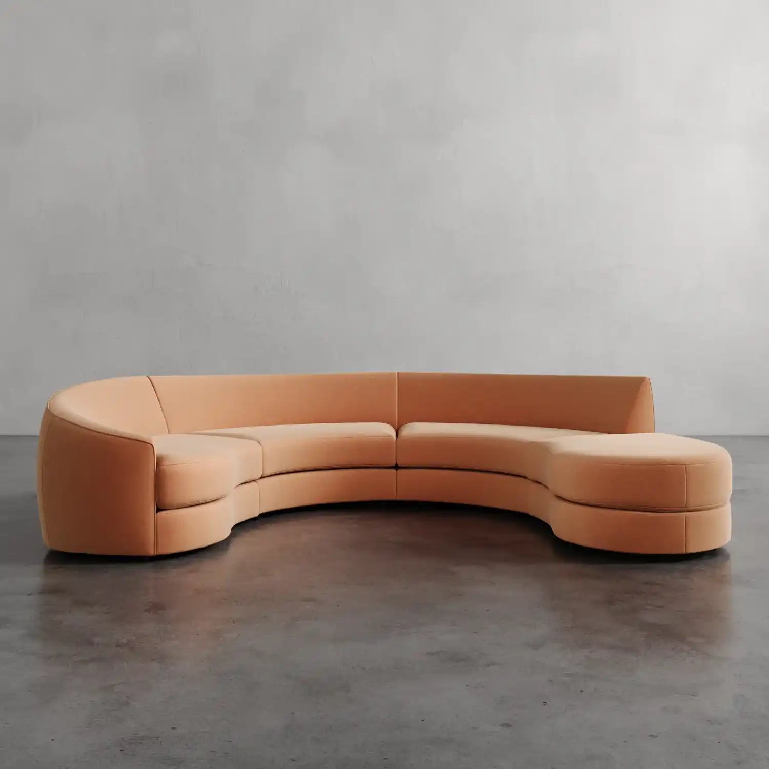 Lemieux et Cie curved sectional in warm leather, sculptural serpentine form shown on polished concrete floor against neutral plaster wall.