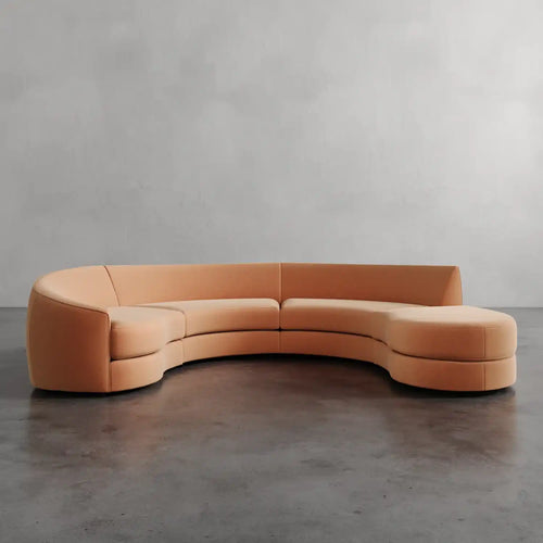 Lemieux et Cie curved sectional in warm leather, sculptural serpentine form shown on polished concrete floor against neutral plaster wall.