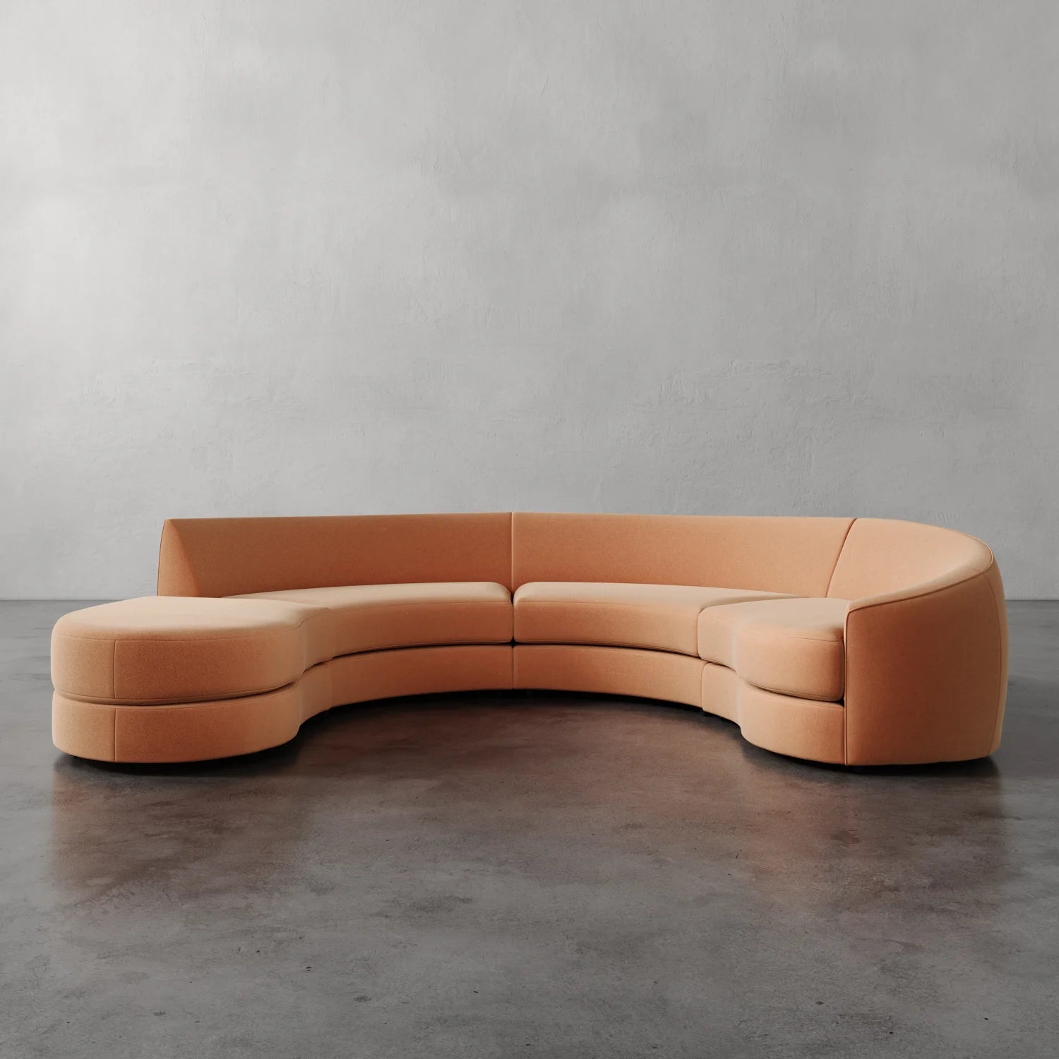 Lemieux et Cie Rulmann sectional in warm peach leather, sculptural curved sofa on polished concrete floors against neutral plaster walls.