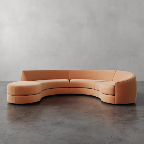 Lemieux et Cie Rulmann sectional in warm peach leather, sculptural curved sofa on polished concrete floors against neutral plaster walls.