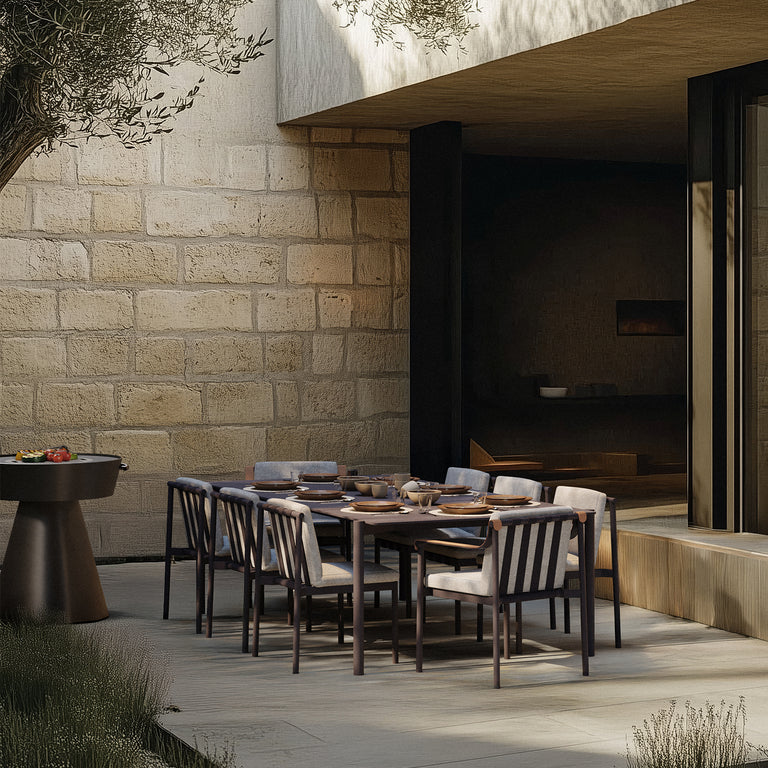 Lemieux Et Cie Hudson Dining Chair SQHudsondining akita grill Outdoor dining setup against a stone wall with modern decor.