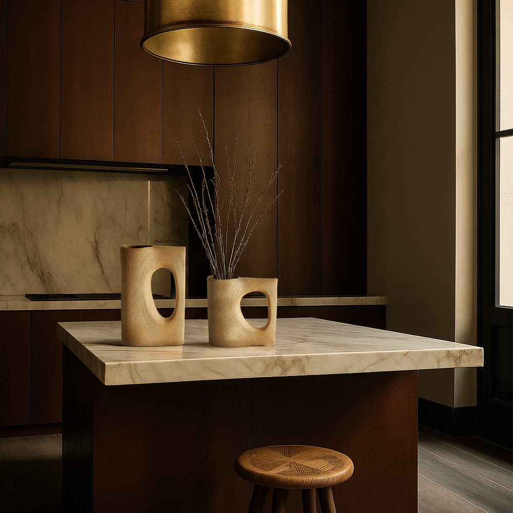 Lemieux et Cie Moreau Vase in vintage brass, sculptural clam shell bowl displayed on marble-topped kitchen island with warm wood cabinetry.