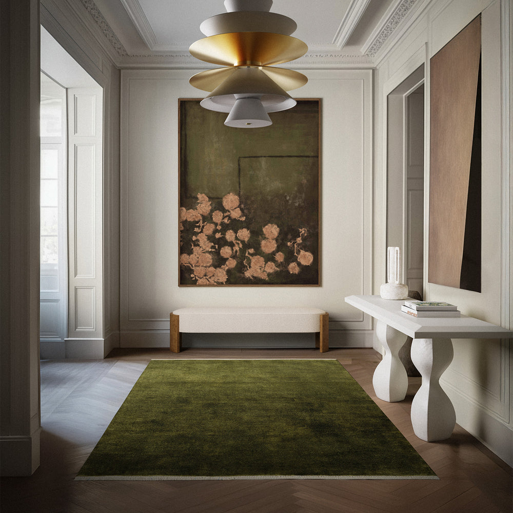 Lemieux et Cie Plume Handmade Wool Rug in moss green, centered in an entry hall with herringbone wood floors and classical molding.