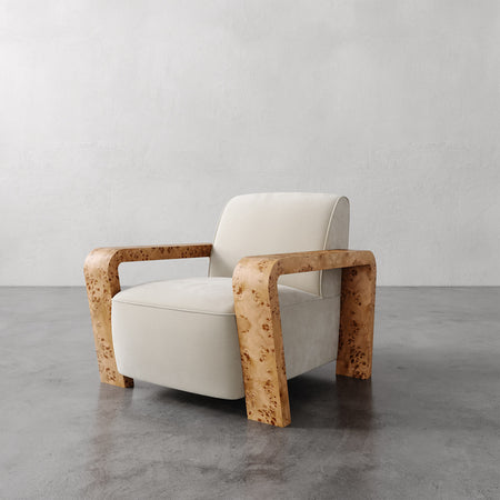 Lemieux et Cie Dumas Chair with blonde burl sculptural arms and ivory upholstered seat, lounge chair shown on concrete floor against neutral plaster walls.