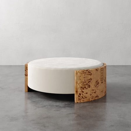 Lemieux et Cie Benoit Coffee Table Ottoman with wire-brushed oak and white marble top, low circular form on polished concrete floor in neutral setting.