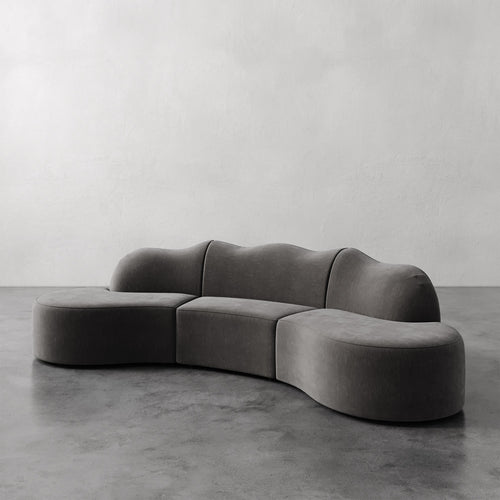Lemieux et Cie Serpentine Sectional Sofa, sculptural modular seating with organic rounded forms, shown on polished concrete floor against white plaster wall.