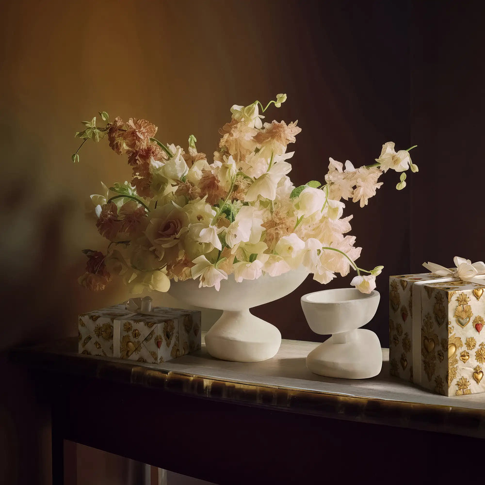 Lemieux et Cie Sacred Heart white and gold wrapping paper wrapping influenced by French devotional art from the 18th century on gift boxes next to a floral arrangement in the Ducoli and Matili bowls