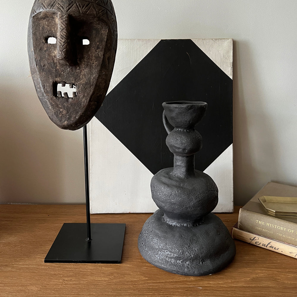 Lemieux et Cie Victoire Vase in black, handcrafted sculptural vessel with stacked spherical forms, styled on wood table with geometric art and tribal mask.