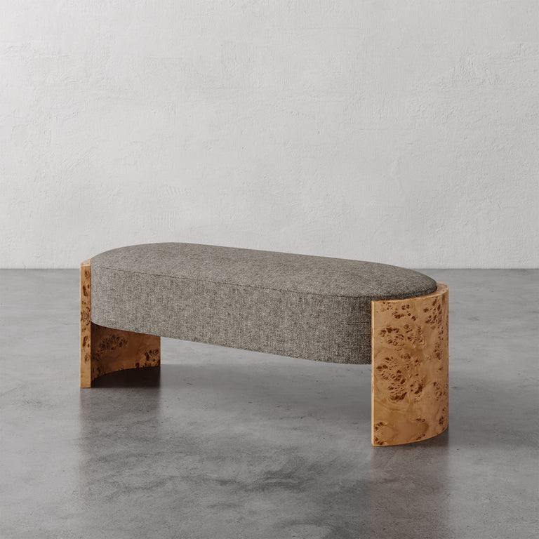 Lemieux et Cie Benoit Custom Upholstered Bench with curved Maple burl legs and gray upholstered seat, shown on polished concrete floor against textured plaster walls.