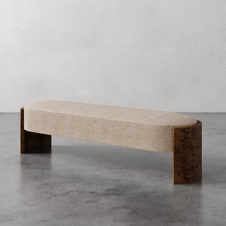Lemieux et Cie Benoit Custom Upholstered Bench with curved Maple burl legs, upholstered seat in neutral bouclé, shown on concrete floor with plaster walls